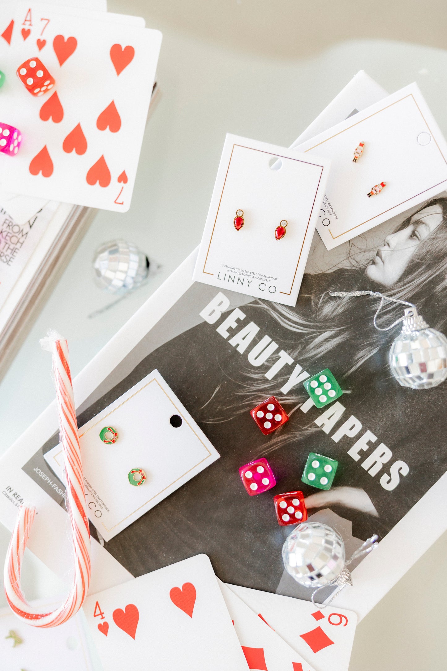 Earring packaging with 'LINNY CO.' branding on a magazine titled 'BEAUTY PAPERS'.