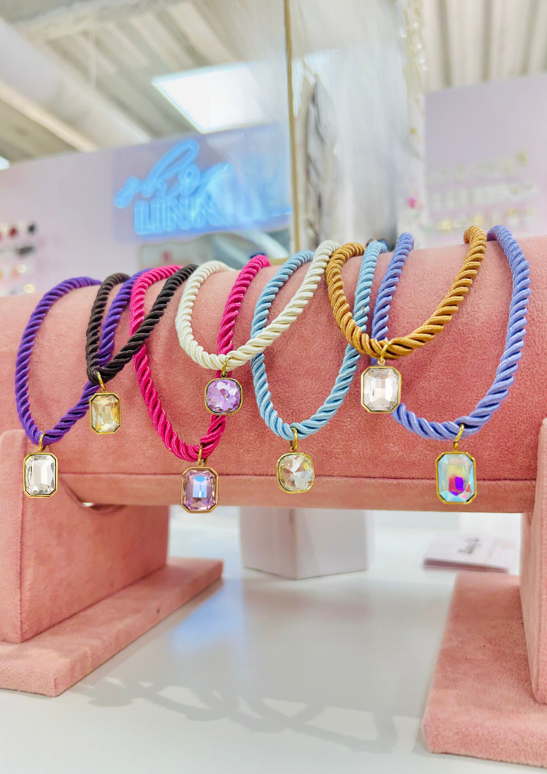 Colorful bracelets with gemstones on a pink stand