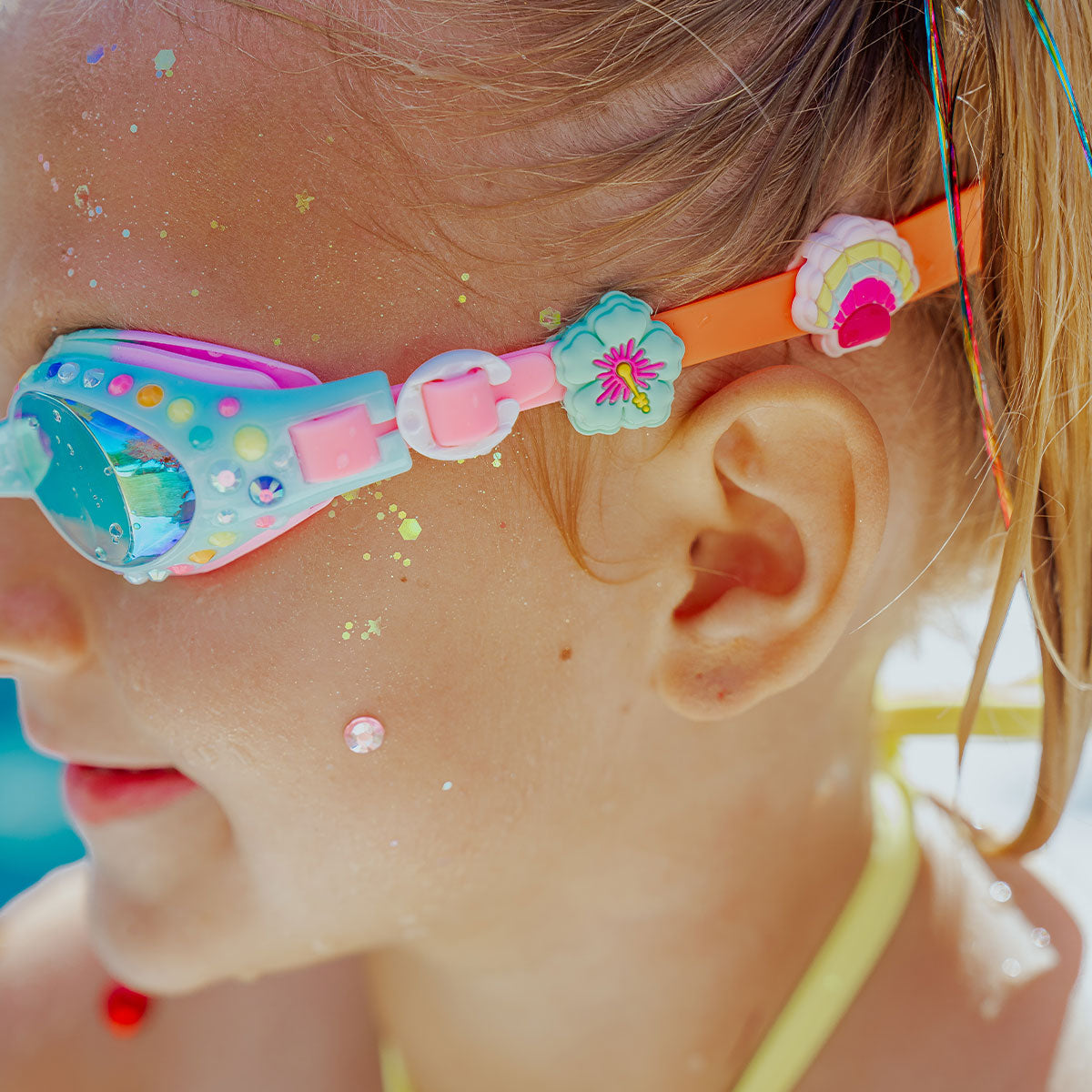 Close-up of a child wearing colorful swim goggles with floral designs.