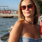 Woman wearing sunglasses and a denim dress by a waterfront