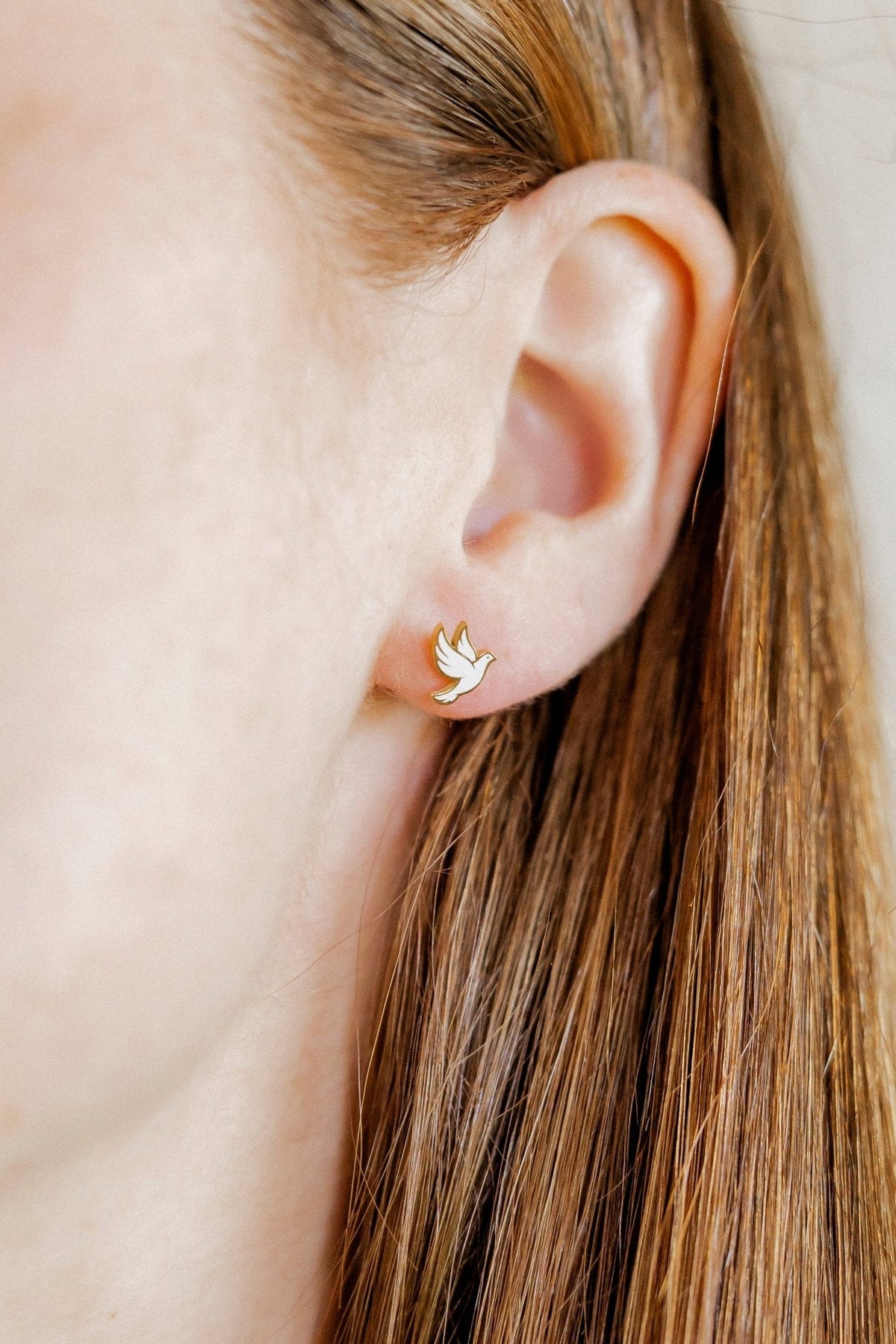 LINNY CO Dove screwback stud earrings, hypoallergenic, waterproof stainless steel with secure screwback backs, shown on model.